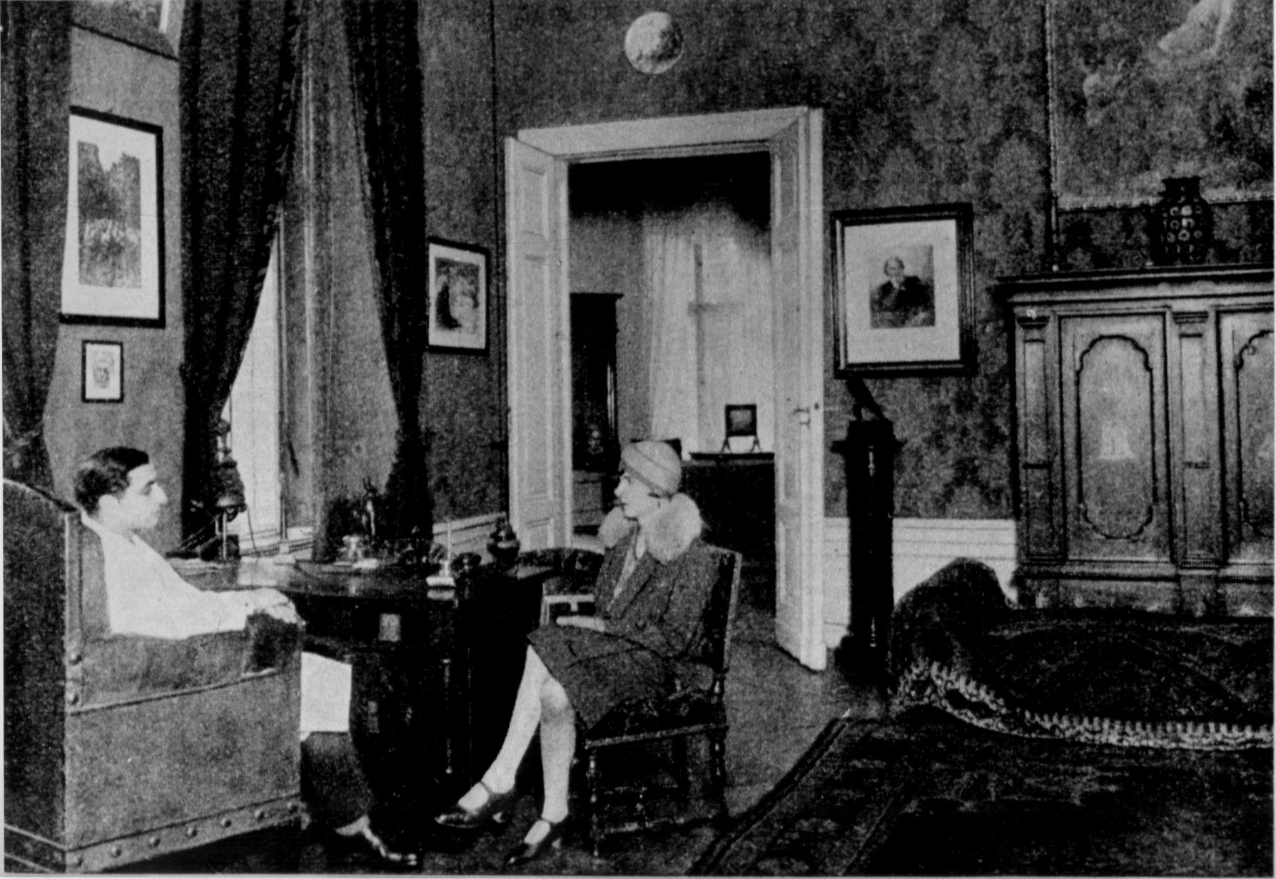 2 photos, the first shows a doctor in a white doctors coat in an armchair in a decorated room with high ceilings. In front of him on the right on a chair sits a transfemale person in a coat with a fur collar and a hat. The second photo shows a devastated office with open shelves almost completely emptied, individual pieces of paper and books on the floor and a devastated desk.